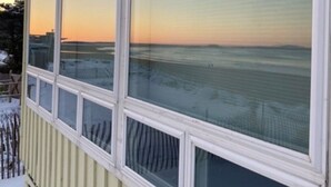 A building with large windows overlooking a snowy landscape. - Popham Beach Direct Oceanfront Cottage Steps to the sand (Phippsburg)