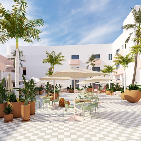 A spacious outdoor patio with checkered flooring, multiple seating areas, and potted plants. - Perla La Paz, Tapestry Collection by Hilton (La Paz)