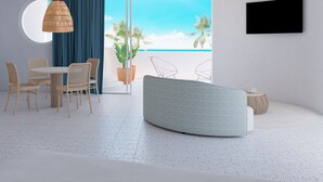A modern living room with a dining area, a ceiling fan, a large window with a view of the beach, and a flat-screen TV mounted on the wall. - Perla La Paz, Tapestry Collection by Hilton (La Paz)