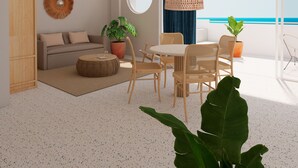 A modern living room with a sofa, coffee table, and chairs, a ceiling fan, and a view of the ocean. - Perla La Paz, Tapestry Collection by Hilton (La Paz)