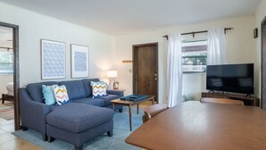 Una sala de estar con un sofá, televisor, mesa de madera y una puerta.