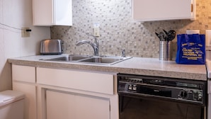 Una cocina con armarios blancos, un lavamanos doble, un tostador, un escurreplatos y un lavavajillas Kenmore.