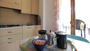 Une cuisine avec des meubles de couleur beige, une cuisinière, un évier et une table sur laquelle se trouvent une cafetière, une tasse et un bol.
