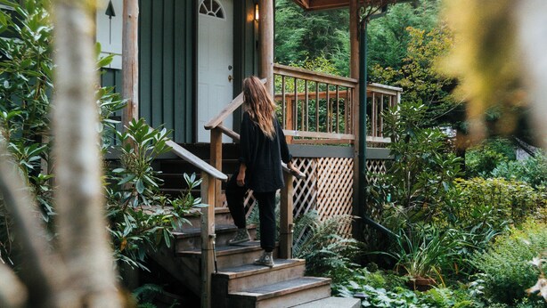 Une cabane en bois avec une véranda, des marches et une porte.