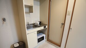 A compact kitchen with a microwave, sink, and a trash bin. - Kanazawa-Hub (Kanazawa)