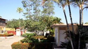 A residential area with a house featuring a small porch, surrounded by various trees and shrubs. - Villas Anacaona (Jarabacoa)