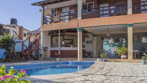 A two-story building with a swimming pool, outdoor seating, and a staircase leading to the upper level. - Villas Anacaona (Jarabacoa)