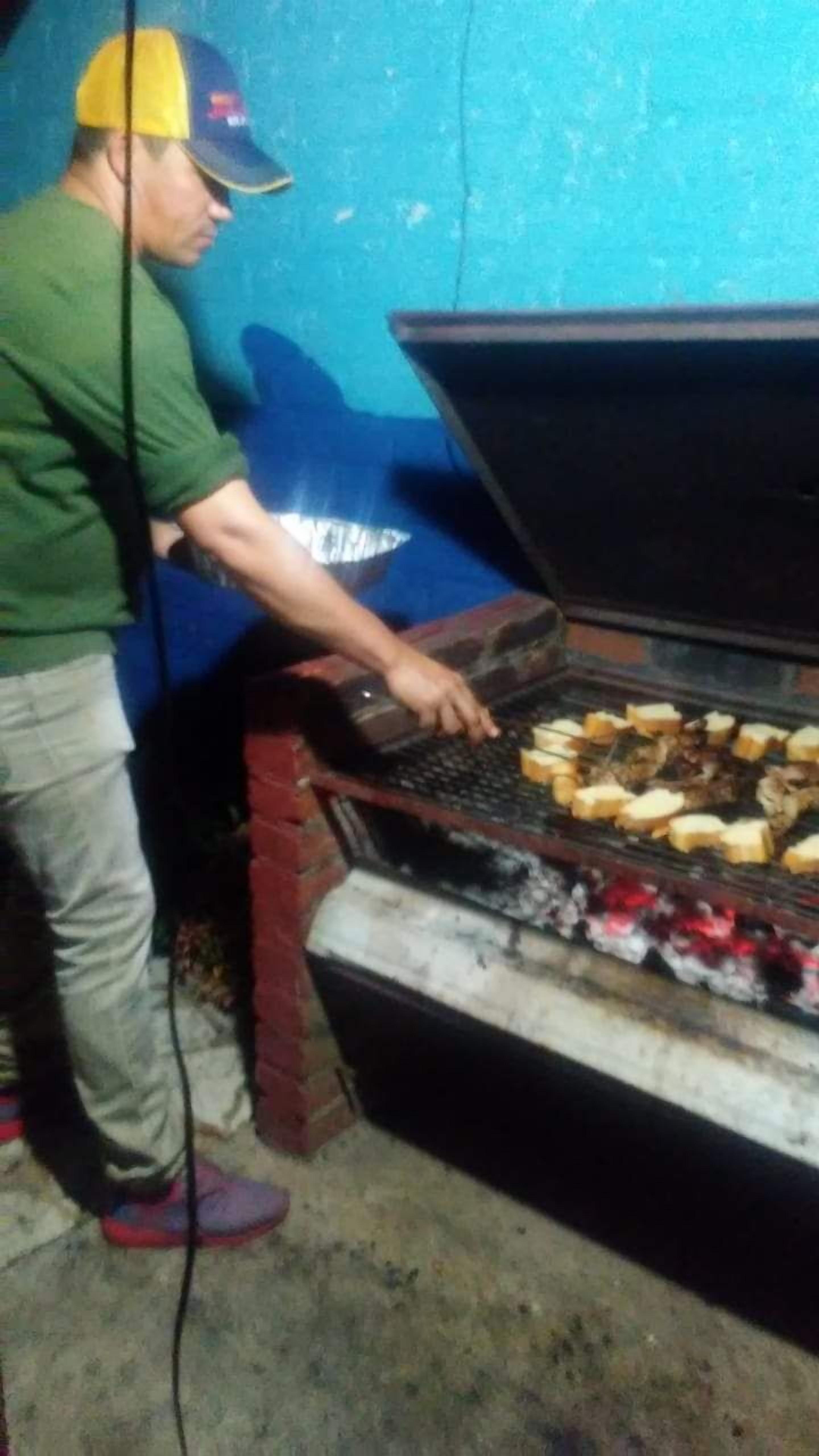 Jemand grillt Essen auf einem offenen Holzkohlegrill.