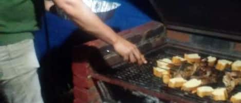 Jemand grillt Essen auf einem offenen Holzkohlegrill.