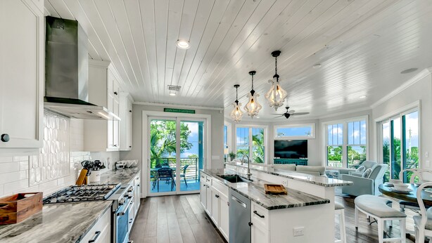 A modern kitchen with white cabinetry, a stainless steel range hood, and a large island with a sink.