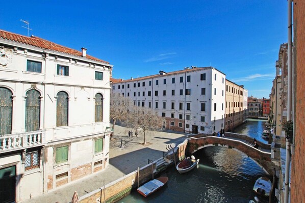 A canal with boats, historic buildings, and a pedestrian walkway.