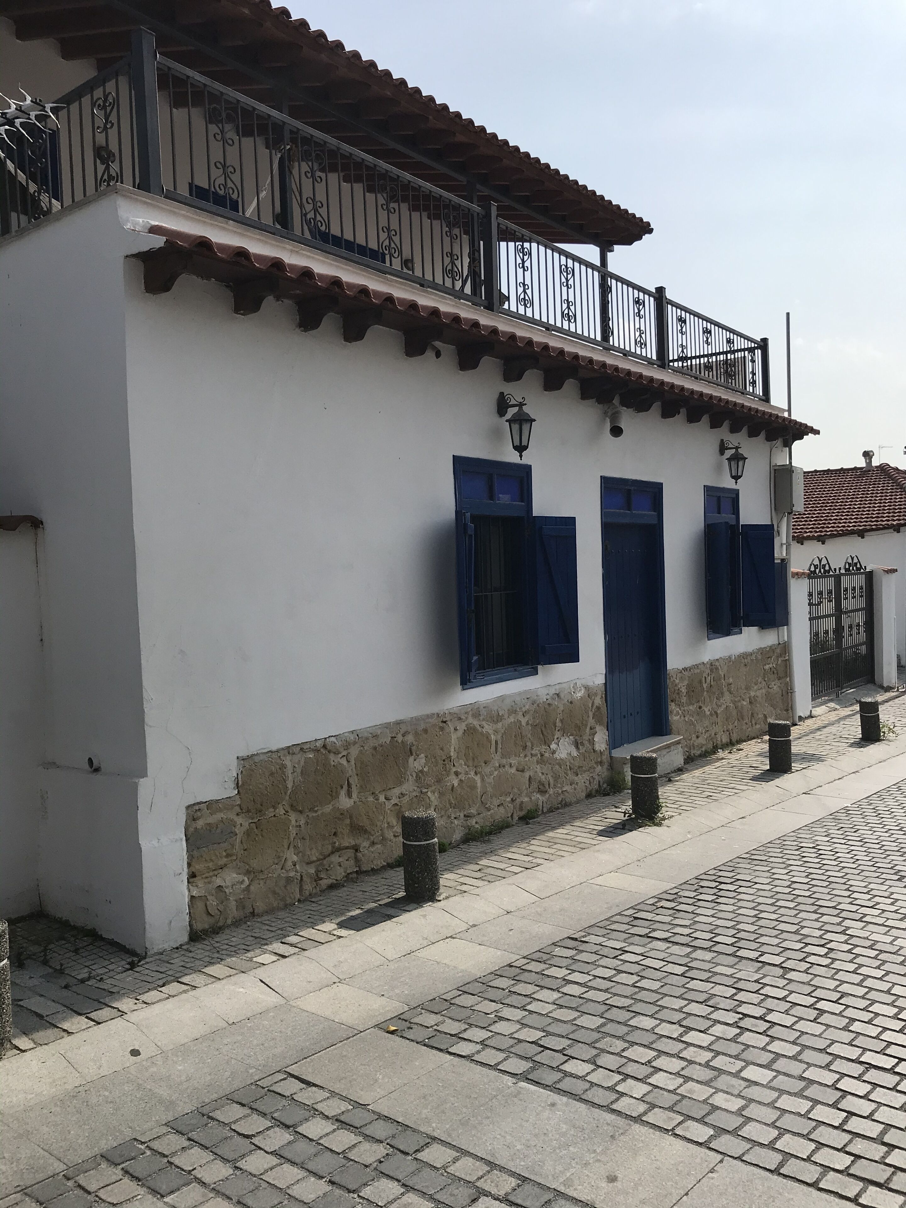 Un bâtiment blanc avec des volets bleus et un balcon doté de rampes en métal.