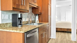 A modern kitchen with granite countertops, stainless steel appliances, and wooden cabinets. - Four Beach Lovers 4 · Full-Size Garden Unit · Solar · Gulf in 50 Steps (Holmes Beach)
