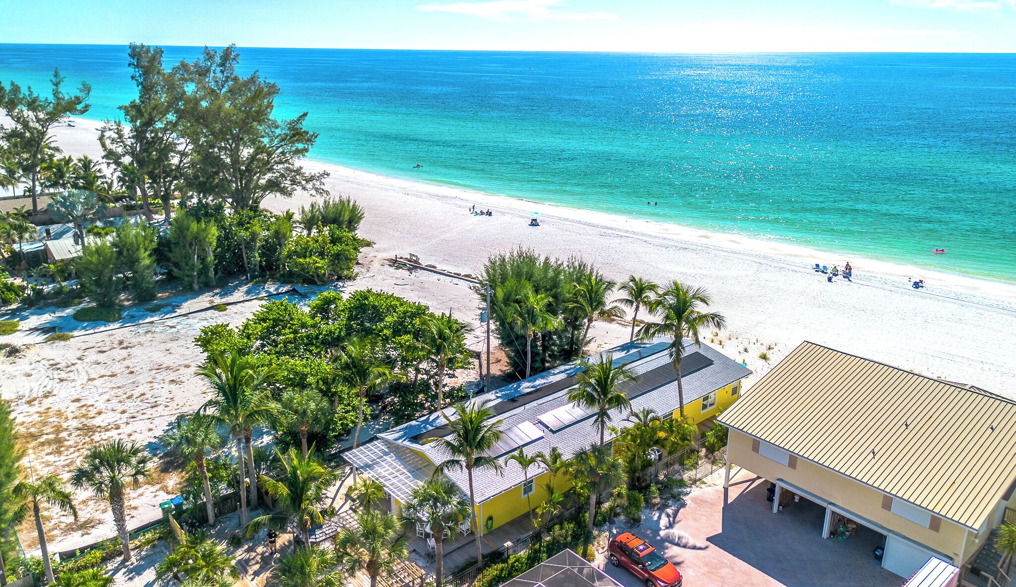 A beach view with a building, palm trees, and a clear blue sea.