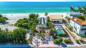 A beachfront property with a swimming pool, a covered patio, and a beach view.