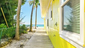 A wooden pathway leading to a yellow building with a beach view.