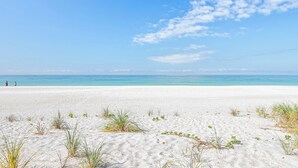 A beach with white sand and clear blue water.