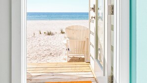 A doorway leading to a beach with a chair and a doormat.