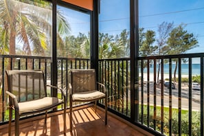 Un balcon avec deux chaises, une vue sur la plage et un ciel dégagé.
