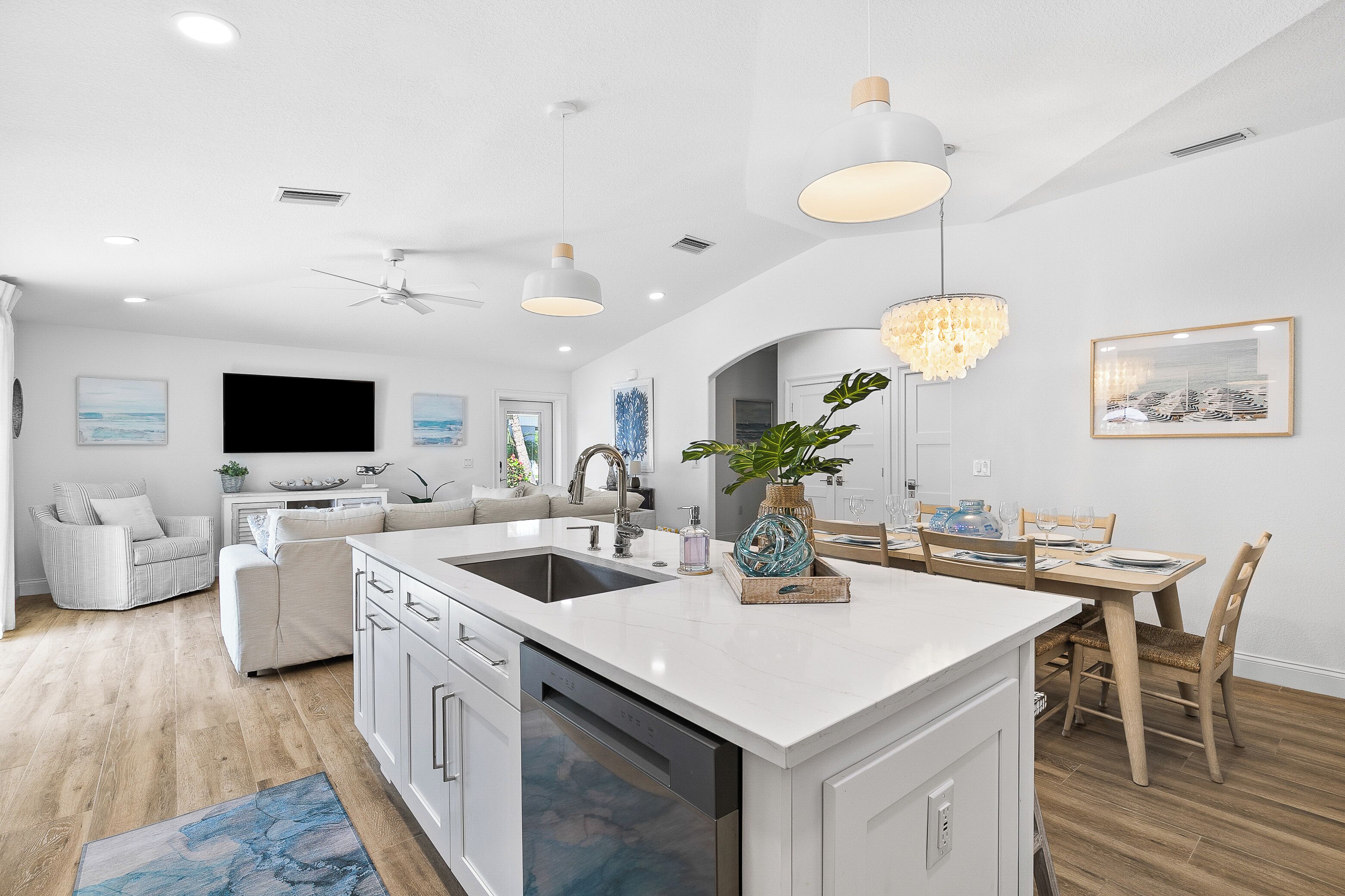 A modern kitchen with white cabinetry, a central island, and pendant lighting.