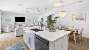 A modern kitchen with white cabinetry, a central island, and pendant lighting.