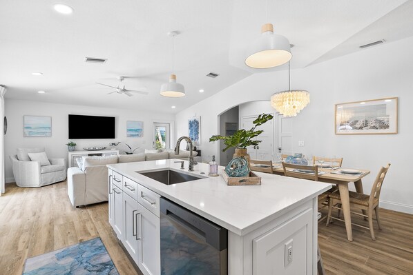 A modern kitchen with white cabinetry, a central island, and pendant lighting.