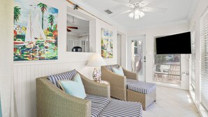 A sunlit room with wicker furniture, a ceiling fan, and artwork on the walls. - Anna Cabana Bungalow #1. Steps to Gulf.  Shared Heated Pool. (Holmes Beach)