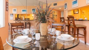 A dining area with a round glass table, chairs, and a central plant.