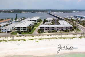 Ein Küstenhotel mit mehreren Gebäuden, einem Strand und einer Brücke im Hintergrund.
