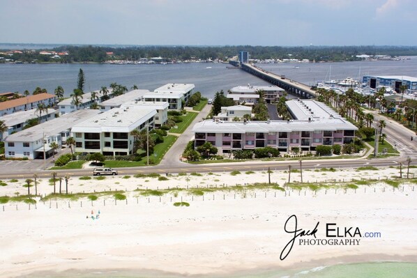 A coastal hotel with multiple buildings, a beach, and a bridge in the background.
