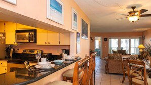 A kitchen with a central island, dining area with chairs, and a living room with a sofa.