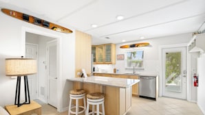 A modern kitchen with a central island, wooden cabinets, and a built-in dishwasher.