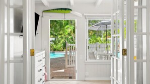 A view from a room with a white door leading to a pool area, a white cabinet, and a window with blinds.