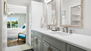 A bathroom with a large vanity, two sinks, and a mirror with decorative trim. - Bay Watch 6A · Dock · Bay & Gulf Access (Bradenton Beach)