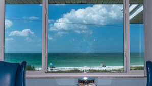 A view from a room with a large window overlooking a beach.