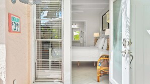 Una habitación con cama, una silla, una lámpara y una ventana con persianas.