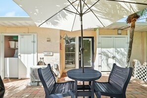 Eine Terrasse im Freien mit einem runden Tisch, zwei Stühlen, einem Deckenventilator und einem Schild, das einen Waschbereich kennzeichnet.