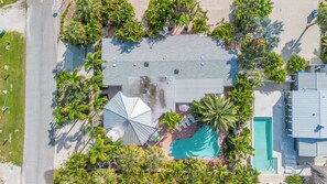 Ein Luftbild eines Anwesens mit Schwimmbad, überdachter Terrasse und umliegenden Palmen.