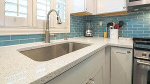 A kitchen with a double sink, a blender, and a microwave.