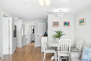 A modern kitchen with white cabinets, a dining table with chairs, and a ceiling fan. - Sea-Esta · Boat Parking · Pool · Pet-Friendly (Holmes Beach)