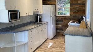 Una cocina moderna con armarios blancos, microondas integrado y refrigerador.