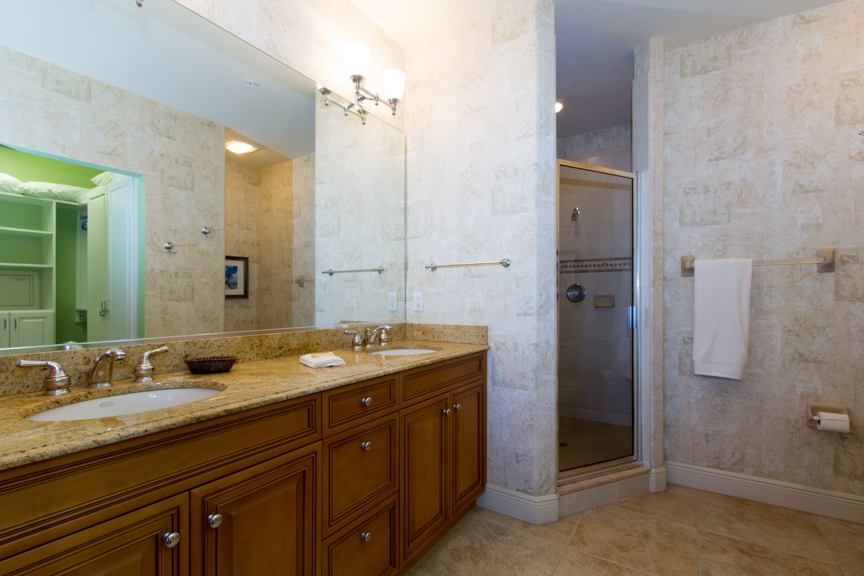 Une salle de bain avec un meuble-lavabo à deux vasques, un grand miroir et une douche à l’italienne.