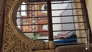 Ein Zimmer mit schmiedeeisernem Geländer, einer gemusterten Bettdecke und Blick auf ein traditionelles Interieur mit Holzboden und Spiegel.