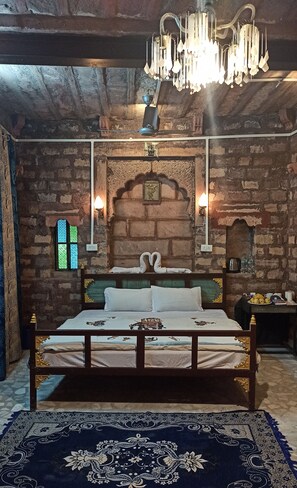 Una habitación con cama, candelabro, chimenea y ventana.
