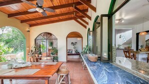 A spacious patio with wooden furniture, a marble countertop, and a ceiling fan. - Private Jungle Palace with Designer Pool (Playa Hermosa)