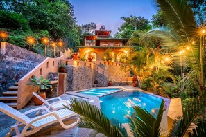 Ein Poolbereich mit Liegestühlen, einer Steinmauer und einem Gebäude mit Balkon.