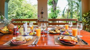 A dining table set with breakfast plates, drinks, and a pineapple. - Private Jungle Palace with Designer Pool (Playa Hermosa)