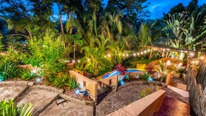 A well-lit outdoor area with stone pathways, a small pool, and seating arrangements. - Private Jungle Palace with Designer Pool (Playa Hermosa)