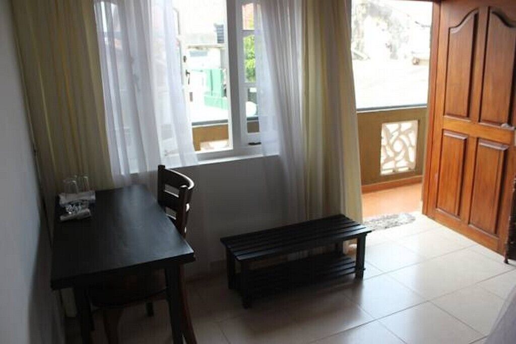 A small dining area with a table and chairs, a bench, and a window with curtains.
