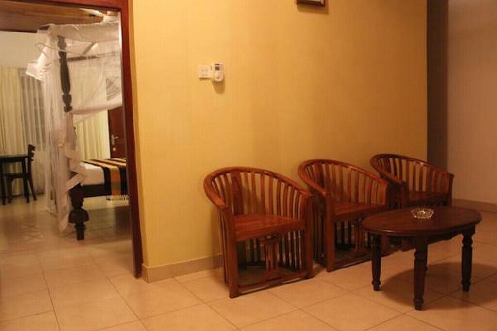 A room with a bed, a wooden chair, a wooden table, and a wall socket.